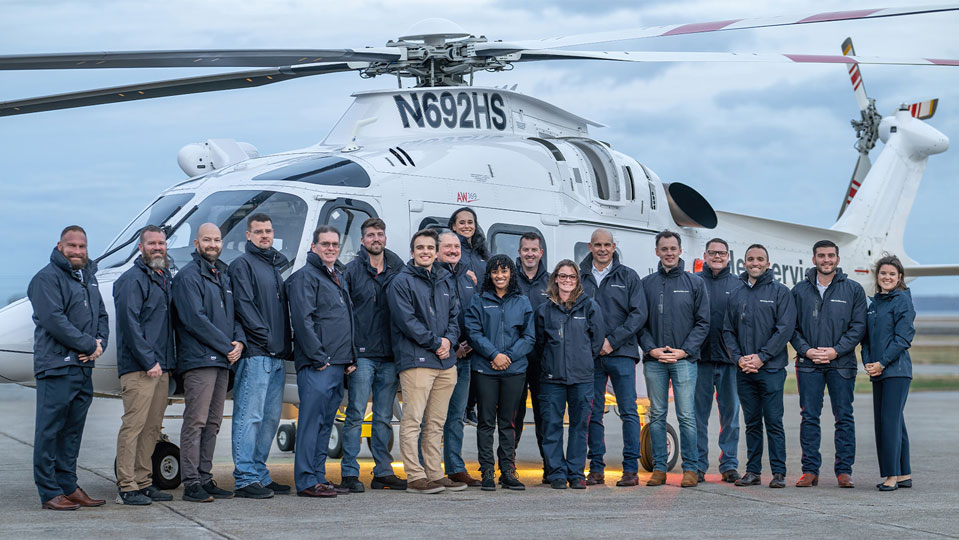 HeliService USA team photo, a HeliService helicopter in background